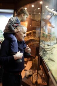 Opa met kind op schouders kijkend in museumvitrine